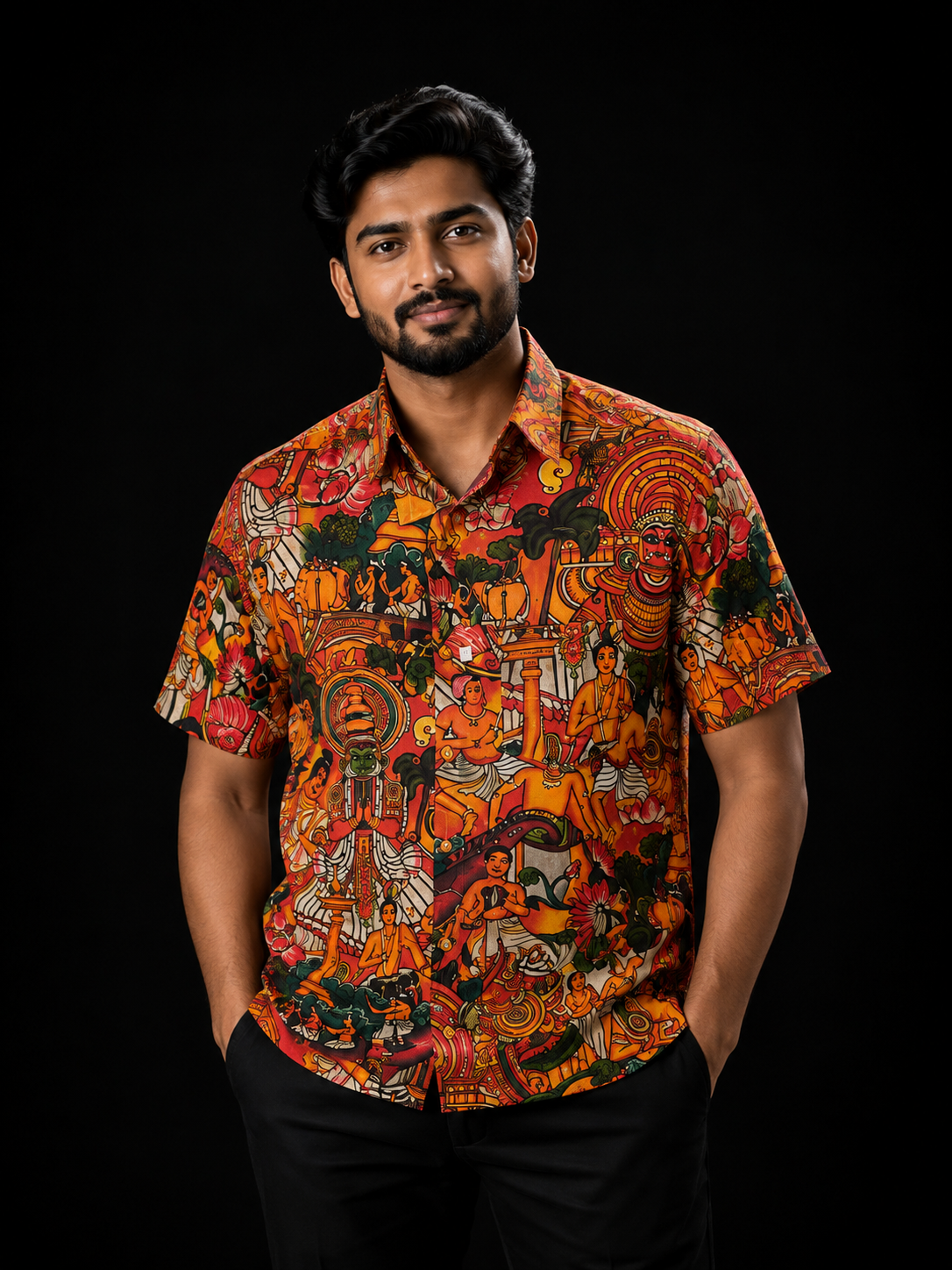 Man wearing a vibrant red and orange all-over print short-sleeve shirt featuring Kerala mural art with Kathakali, Theyyam, and temple motifs